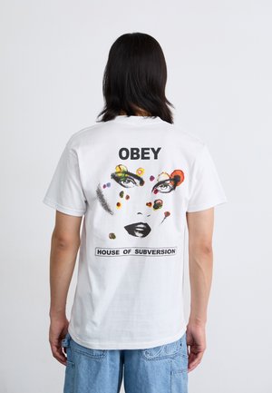 White cotton T-shirt featuring a colorful graphic of a face and text "OBEY" and "HOUSE OF SUBVERSION" on the back. Short sleeves, relaxed fit.