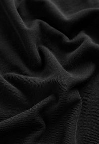 Tissu noir avec une surface lisse et légèrement texturée. Le matériau présente des plis et des froissements doux, indiquant une flexibilité et un tombé léger.