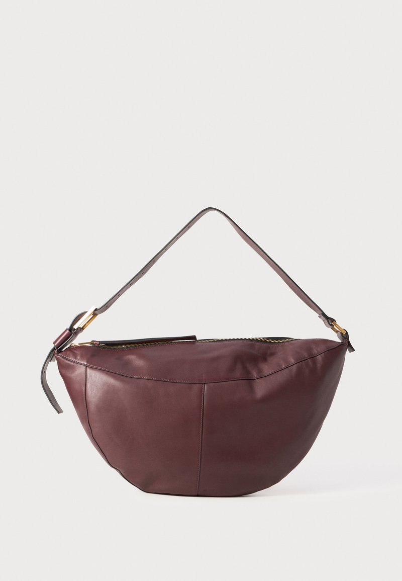 Borsa in pelle color bordeaux con forma curva, dotata di una sola tracolla e hardware in tonalità oro; texture liscia e chiusura con zip.