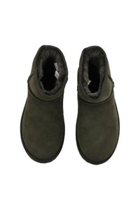Para ciemnozielonych zamszowych botków za kostkę z pluszowym futerkiem w środku, pokazanych z góry na białym tle.