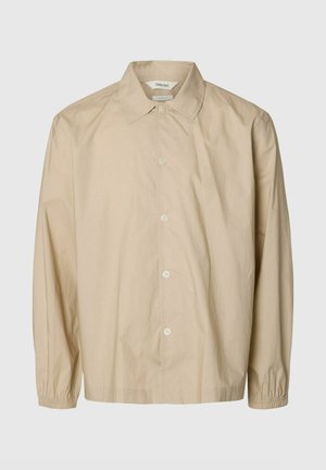 Beige pitkähihaiset nappilistallinen paita kuminauhahihoilla, leveällä kauluksella ja rento istuvuus, esillä yksivärisellä vaaleanharmaalla taustalla.