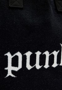 Czarna torba typu tote z materiału filcowego, z dużym białym napisem "punk" w gotyckim kroju pisma, z widocznymi tkaninowymi uchwytami.