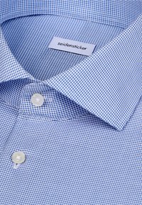 Chemise bleu clair à petits carreaux, boutons blancs et étiquette "seidensticker" à l'intérieur du col.