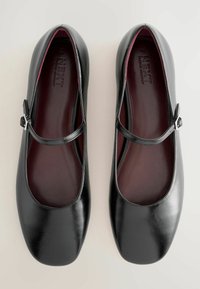 Pair of black leather Mary Jane shoes with adjustable buckle straps and dark red insoles, shown from above on a light background.