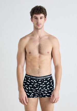 Schwarze Boxer-Shorts mit einem sich wiederholenden Muster von weißen Sonnenbrillen, ausgestattet mit einem Logo-Bund. Glatte Textur, enganliegendes Design und Beinlänge bis zur Mitte des Oberschenkels.