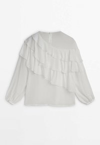 Blusa bianca con maniche lunghe, caratterizzata da una riga arricciata diagonale nella parte anteriore, tessuto morbido e chiusura a bottoni sul retro.
