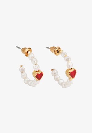 Złote kolczyki koła zdobione białymi perłami, ozdobione czerwonymi kamieniami w kształcie serca. Projekt zawiera teksturowane elementy dla dodatkowego efektu detalu.