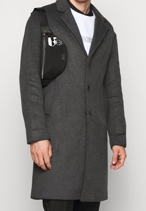 Grijze wollen mix jas met een getailleerde pasvorm, metgelapte revers en een enkele knoopsluiting. Gecombineerd met een zwarte schoudertas met een grafisch ontwerp.