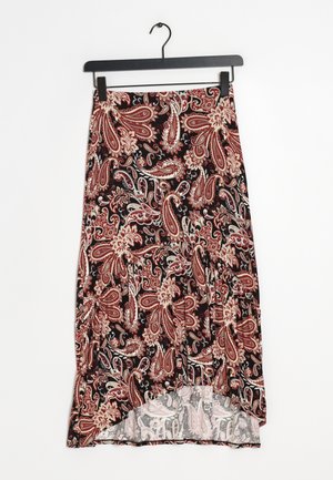 Jupe noire avec un motif floral paisley rouge et beige, ourlet asymétrique, suspendue à un cintre noir sur fond blanc.