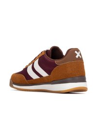 Zapatillas de ante marrón y sintético color granate con rayas blancas, suela de goma y cuello acolchado. Presentan un acento marrón en el talón con un logo blanco.