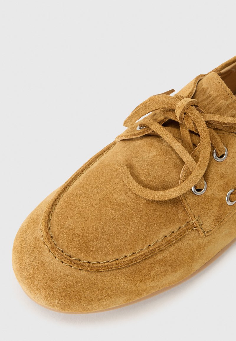 Wildleder-Schnürschuh in Tan-Farbe, mit abgerundetem Zehenbereich, Steppnaht und Metallösen für die Schnürsenkel. Weiche Textur, lässiges Design.
