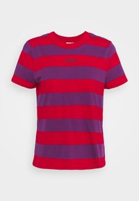 Röd och lila randig t-shirt med korta ärmar, rund hals och en diskret "Wrangler"-logotyp centrerad på bröstet. Slät bomullstextur.