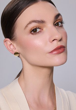 Złote okrągłe kolczyki wkręty noszone w eleganckiej fryzurze; gładka tekstura skóry; neutralny odcień szminki; subtelne akcenty makijażu wokół oczu.