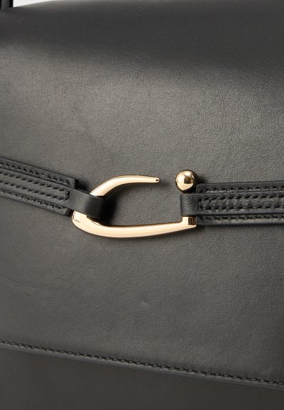 Mustapohjainen nahkalaukku, jossa on kultasävyinen metalliklipsi, teksturoitu pinta ja yksityiskohtaiset tikkausreunat.