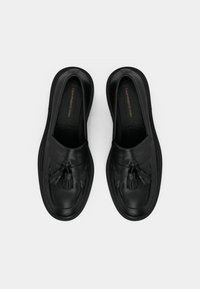 Mustat nahka loaferit sileällä pinnalla, joissa on koristeellinen tupsu etuosassa ja litteä kumipohja.