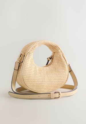Beige woven crescent-shaped handbag with circular cut-out handle and adjustable leather shoulder strap on white background.