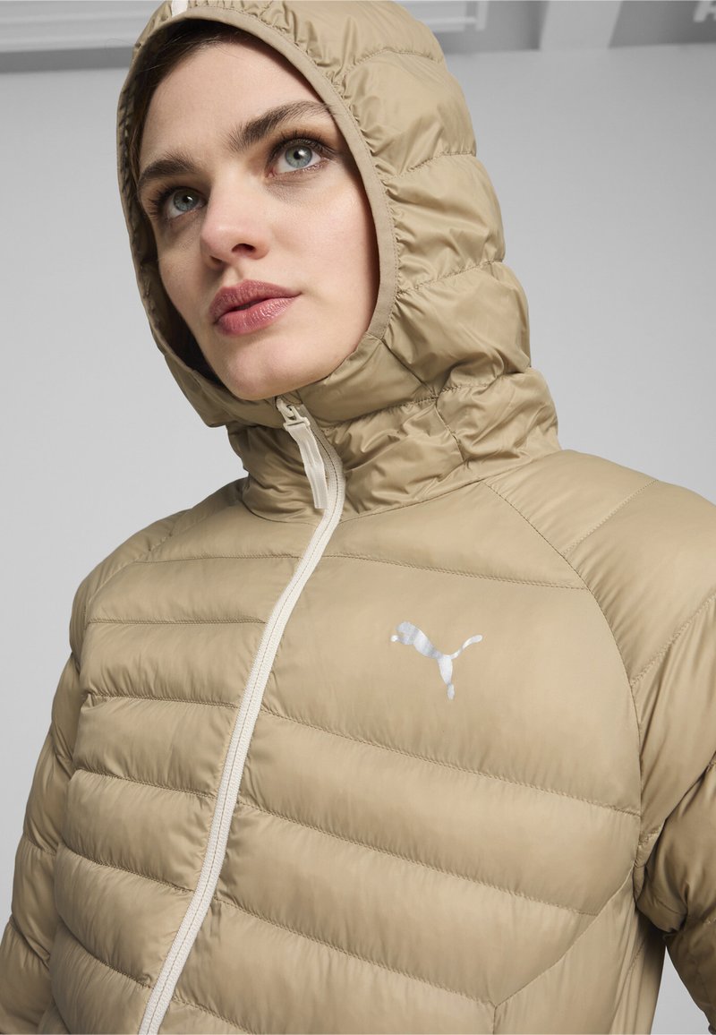 Chaqueta de plumas beige con textura acolchada, cuenta con una capucha y un zip de contraste. Logotipo blanco en el área del pecho izquierdo. Acabado de material suave.