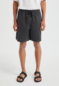 Shorts noirs en tissu léger, dotés d'une taille élastique avec un cordon de serrage, coupe droite et poches latérales.