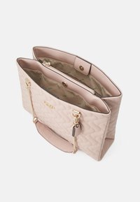 Borsa beige trapuntata con hardware dorato, due scomparti, chiusura a scatto e accentuazione a catena. L'interno presenta una fodera a fantasia.