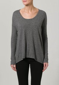Pull gris en tissu tricoté doux avec un large col rond, des manches longues côtelées et un ourlet incurvé, associé à un pantalon noir.
