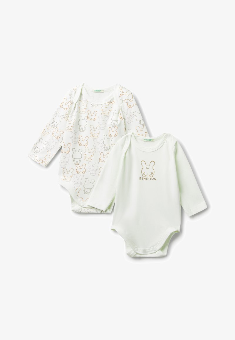 Dvě bílé dětské body s dlouhým rukávem, jedno s vzorem s králičími obličeji, druhé s jedním králičím obličejem a textem "Benetton".