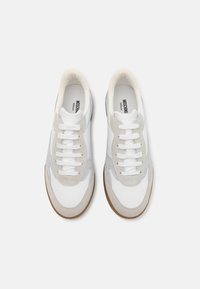 Vita och grå sneakers med en kombination av läder och mockamaterial. Har runda tår, platta skosnören och en gummisula.