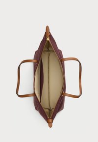 Bordová kožená taška s hnedými textúrovanými uchami a zlatým zipsom. Interiér je vybavený svetlo béžovou podšívkou s dvoma priehradkami.