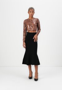 Leopard print cropped top with long sleeves, black flared skirt, and black heels. Smooth texture, form-fitting silhouette.