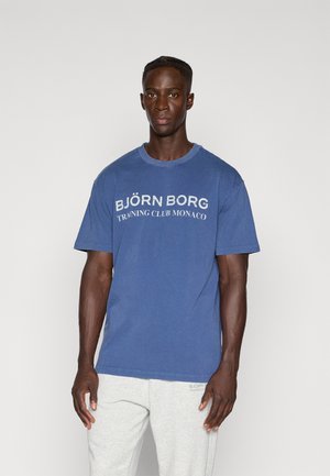 Mėlyna medvilnės marškinėliai su trumpomis rankovėmis, ant krūtinės su baltu tekstu "BJÖRN BORG TRAINING CLUB MONACO". Paprastas dizainas, laisvas kirpimas.