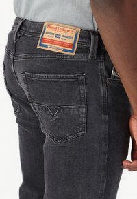 Jeans de mezclilla negra con un acabado desgastado, que cuentan con un bolsillo trasero con forma, costuras en contraste y una etiqueta de cuero con la marca en la cintura.
