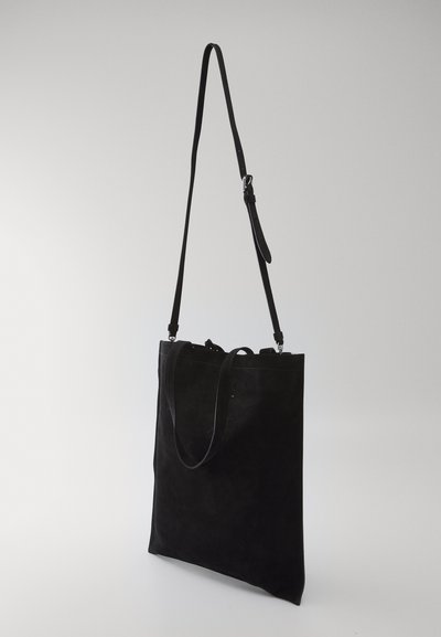 Geantă tote din suede negru cu o curea lungă, ajustabilă. Geanta are un design minimalist, o textură netedă și nu conține accesorii vizibile.