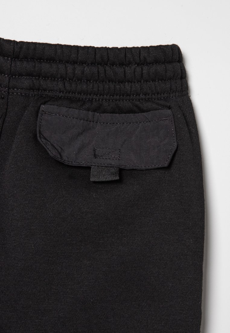 Pantalones de chándal negros con una cintura elástica, tejido texturizado y un bolsillo trasero rectangular con un lazo de tela.