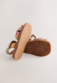 Sandales multicolores avec brides supérieures texturées, base beige et semelle en caoutchouc avec un motif en zigzag pour l'adhérence.
