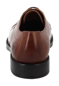 Scarpa elegante da uomo in pelle marrone con punta arrotondata, texture liscia, dettagli di cuciture sottili e suola in gomma nera. Vista posteriore che mostra il design slip-on.