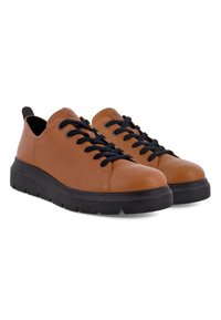Paire de baskets basses en cuir marron avec lacets noirs et semelles épaisses en caoutchouc noir sur fond blanc.