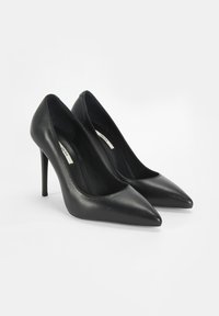 Schwarze Leder hohe Absätze haben eine spitze Zehenpartie, ein schlankes Design und einen Stiletto-Absatz. Das Innenleben ist glatt und hat eine gepolsterte Fußbett.