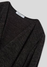 Cardigan nero lavorato a maglia con scollo a V profondo, tessuto strutturato e sottili accenti di filo metallico. L'etichetta riporta "Terranova", taglia 5.