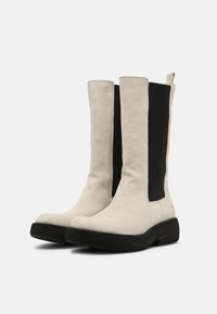 Skórzane kozaki do kolan z białym przodem i czarnymi elastycznymi panelami bocznymi, charakteryzujące się płaską czarną podeszwą i gładką fakturą.