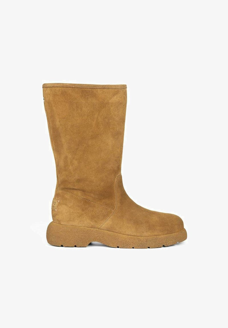 Botín de ante hasta la mitad de la pantorrilla en color marrón, con puntera redondeada, superficie texturizada y suela de goma resistente. Diseño simple y limpio con acentos mínimos.