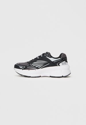 Crne i sive atletske tenisice s mrežastim gornjim dijelom, gumenim potplatom i karakterističnim bijelim naglascima. Imaju dizajn s vezicama i amortiziranu srednju potplat.