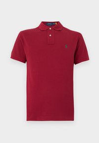Polo rouge à manches courtes avec deux boutons et petit logo vert brodé sur la poitrine gauche.