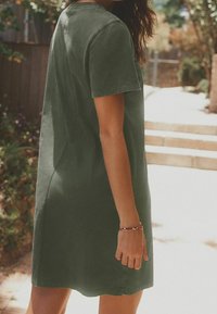 Kurzärmliges, knielanges Kleid aus dunkelgrüner Baumwolle. Es verfügt über einen Rundhalsausschnitt und einen entspannten Schnitt, mit einer glatten Textur und minimalen Designdetails.