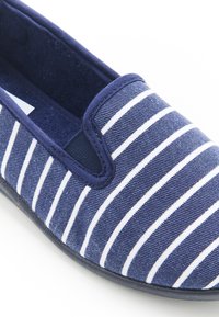 Scarpa slip-on blu navy realizzata in tessuto testurizzato con strisce orizzontali bianche, dotata di colletto imbottito e suola piatta in gomma.