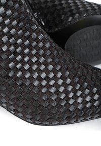 Czarny, pleciony botek za kostkę o teksturowanym, kratkowanym wzorze, wykonany ze skóry i tkaniny. Posiada okrągły czubek i gładką podeszwę.