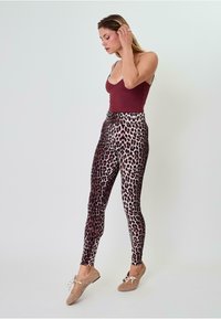 Leopardo rašto legginsai iš tamprios medžiagos su prigludusia forma. Juosmuo yra aukštas, su tamsiai ir šviesiai rudos spalvos dėmėmis ant kreminės bazės.
