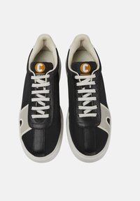 Svarta sneakers med vita snören, ovandel i läder, kontrasterande ljusgrå detaljer, rund logotab i orange och vadderad krage för komfort.