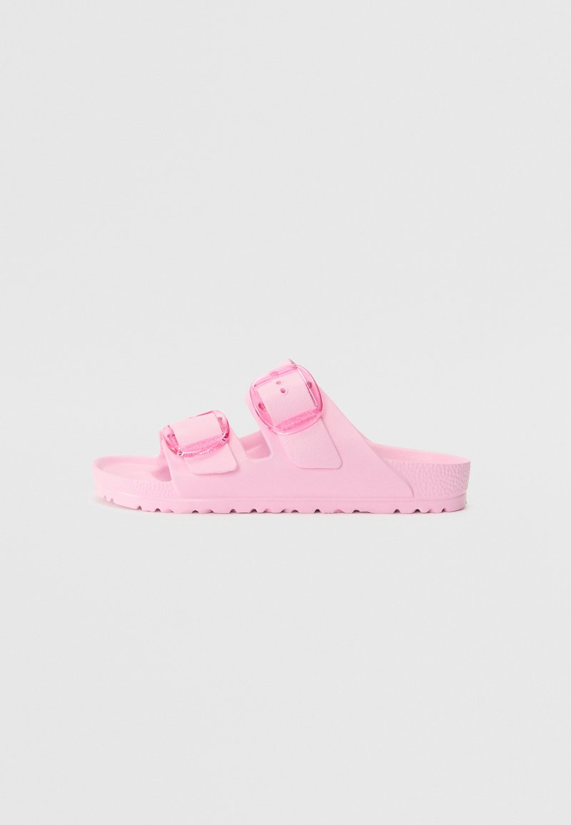 Rosa slip-on sandaler i gummi. Har två justerbara remmar med genomskinliga spännen, texturerad fotbädd och en räfflad sula för grepp.