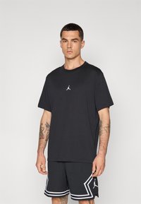 Crna pamučna majica s okruglim izrezom, s malim bijelim Jumpman logotipom na prsima. Nositi s crnim mrežastim šortsevima s bijelim detaljima.