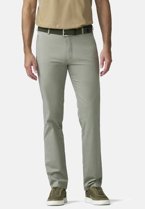 Homme portant un pantalon gris clair à coupe droite, une ceinture tissée vert olive, une chemise beige et des baskets vert olive sur fond blanc.