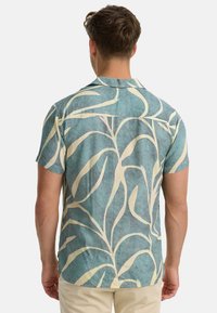 Short-sleeve shirt in teal with white abstract leaf pattern, featuring a button-down collar and a relaxed fit, made from lightweight fabric.